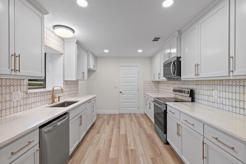 403 East 8th Street Prosper, TX 75078 - Photo 9 of 34 a kitchen with a sink dishwasher stove and white cabinets with wooden floor