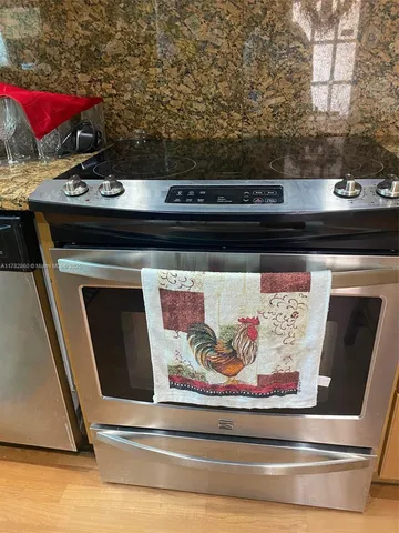 a room with stainless steel appliances granite countertop a stove and a microwave oven