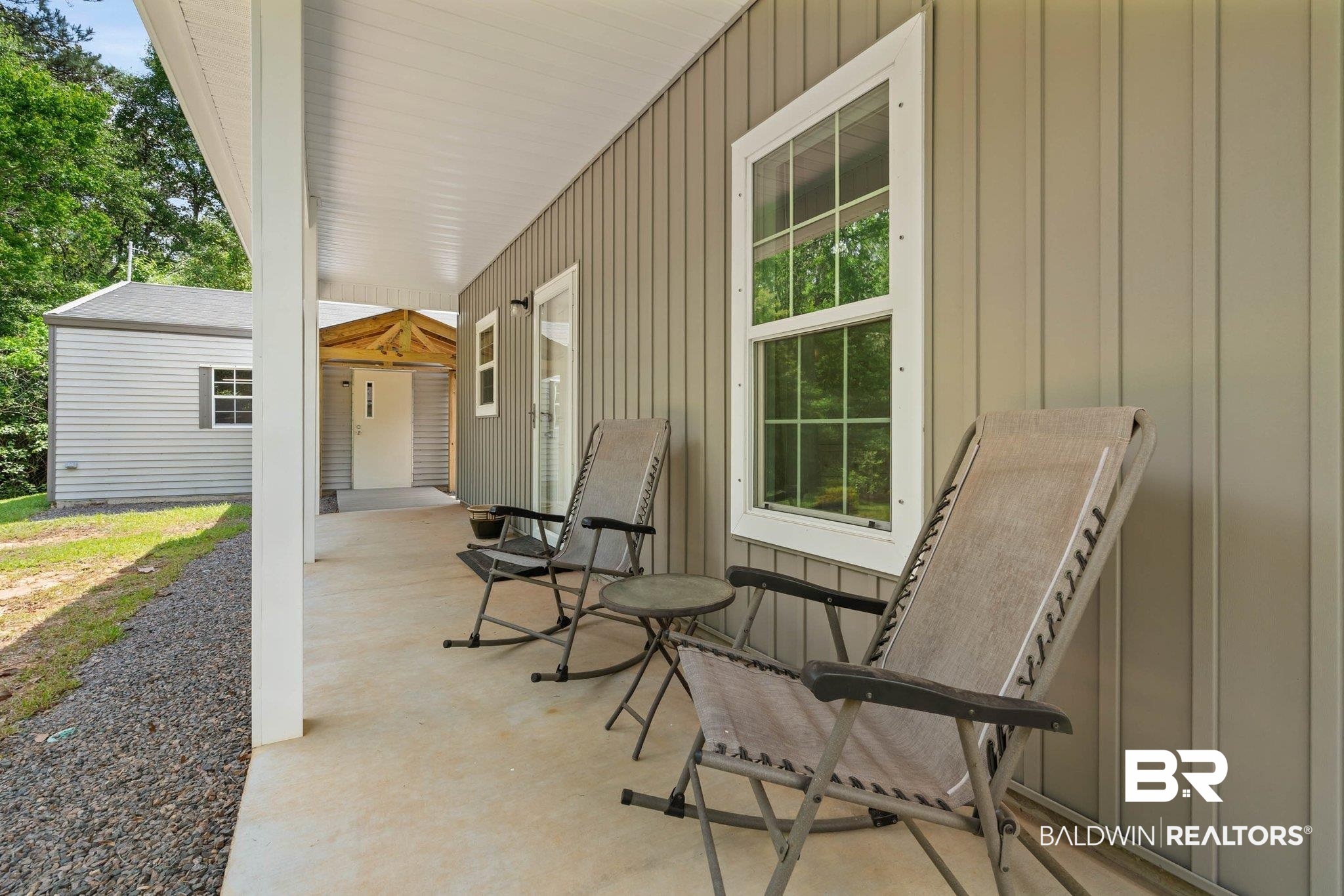 13751 Fish River Acres Circle Foley, AL 36535 - Photo 22 of 26 Covered concrete porch with light gray vertical siding, white trim windows, and a gravel perimeter