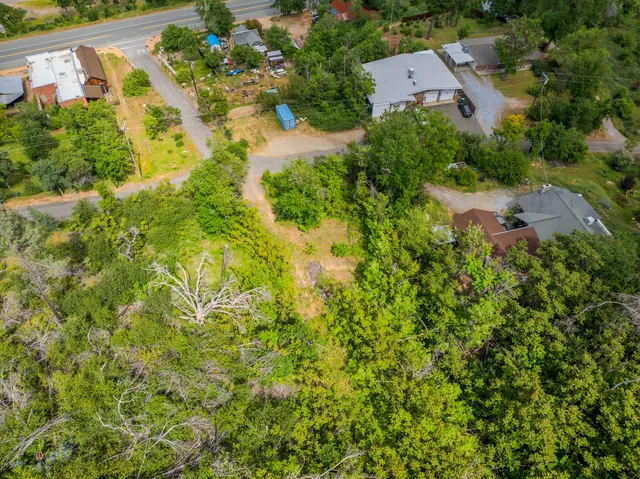 an aerial view of residential house with outdoor space and trees all around
