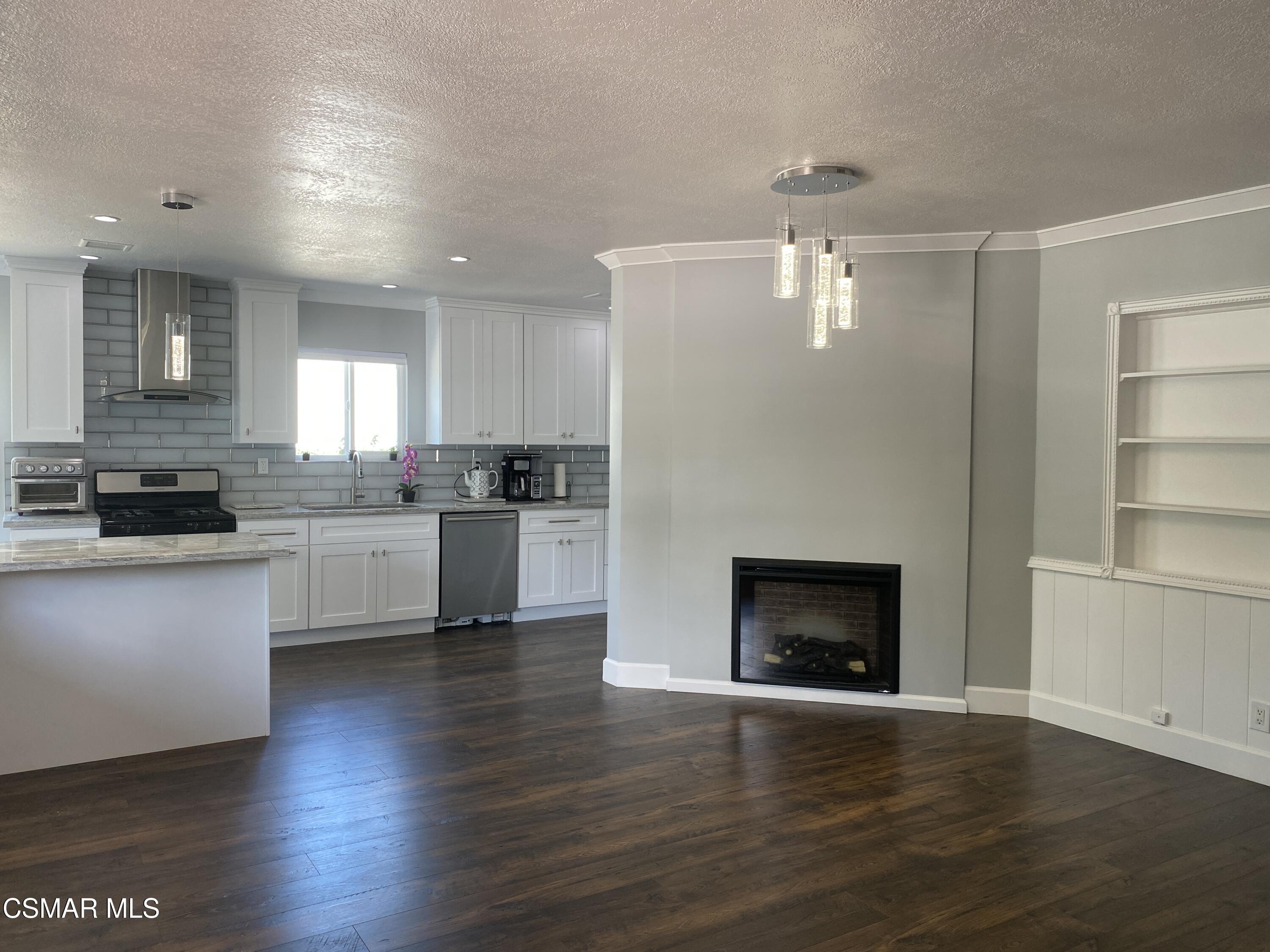4511 Barnard Street Simi Valley, CA 93063 - Photo 5 of 25 a kitchen with granite countertop wooden floors stainless steel appliances and white cabinets