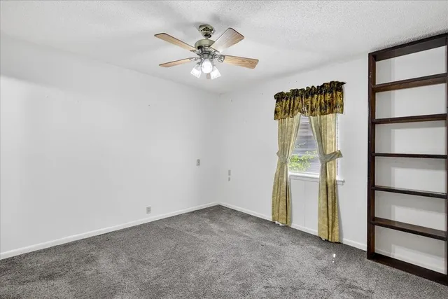 an empty room with closet and a chandelier fan
