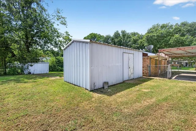a view of a backyard with a barn and a large tree
