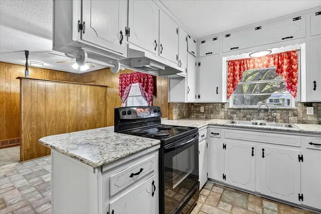 a kitchen with granite countertop a sink a stove and wooden cabinets