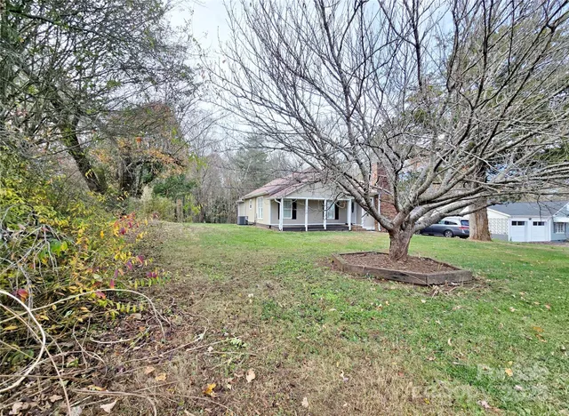 a view of a yard in front of a house with large trees