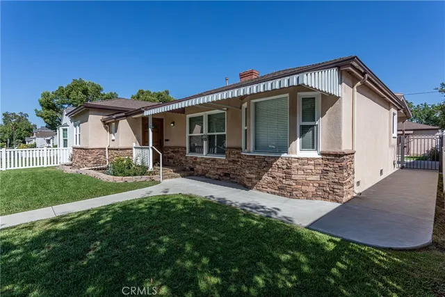 a view of a house with a yard potted plants and large tree