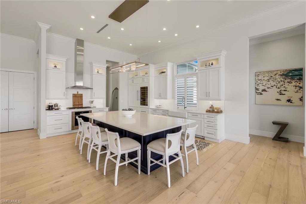 16415 Seneca Way Naples, FL 34110 - Photo 23 of 50 a kitchen with stainless steel appliances kitchen island granite countertop a table chairs and a refrigerator