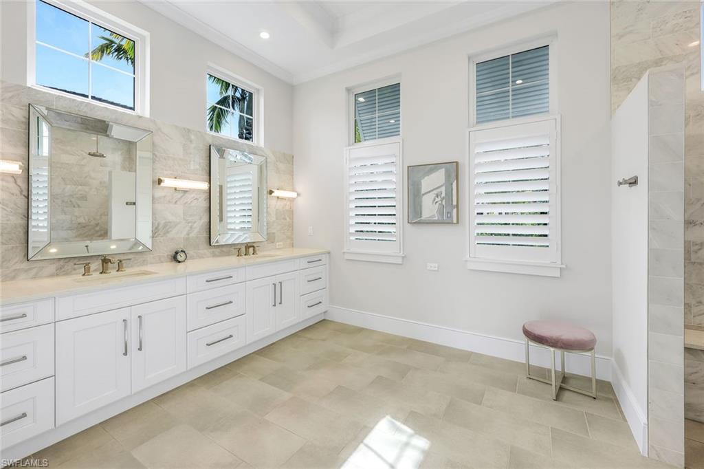 16415 Seneca Way Naples, FL 34110 - Photo 26 of 50 a bathroom with double vanity sink a mirror and a bathtub