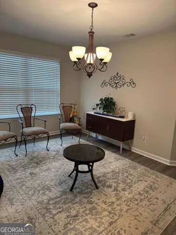 a living room with couches a dining table and a chandelier