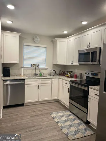 a kitchen with stainless steel appliances granite countertop a stove top oven a sink a microwave and cabinets