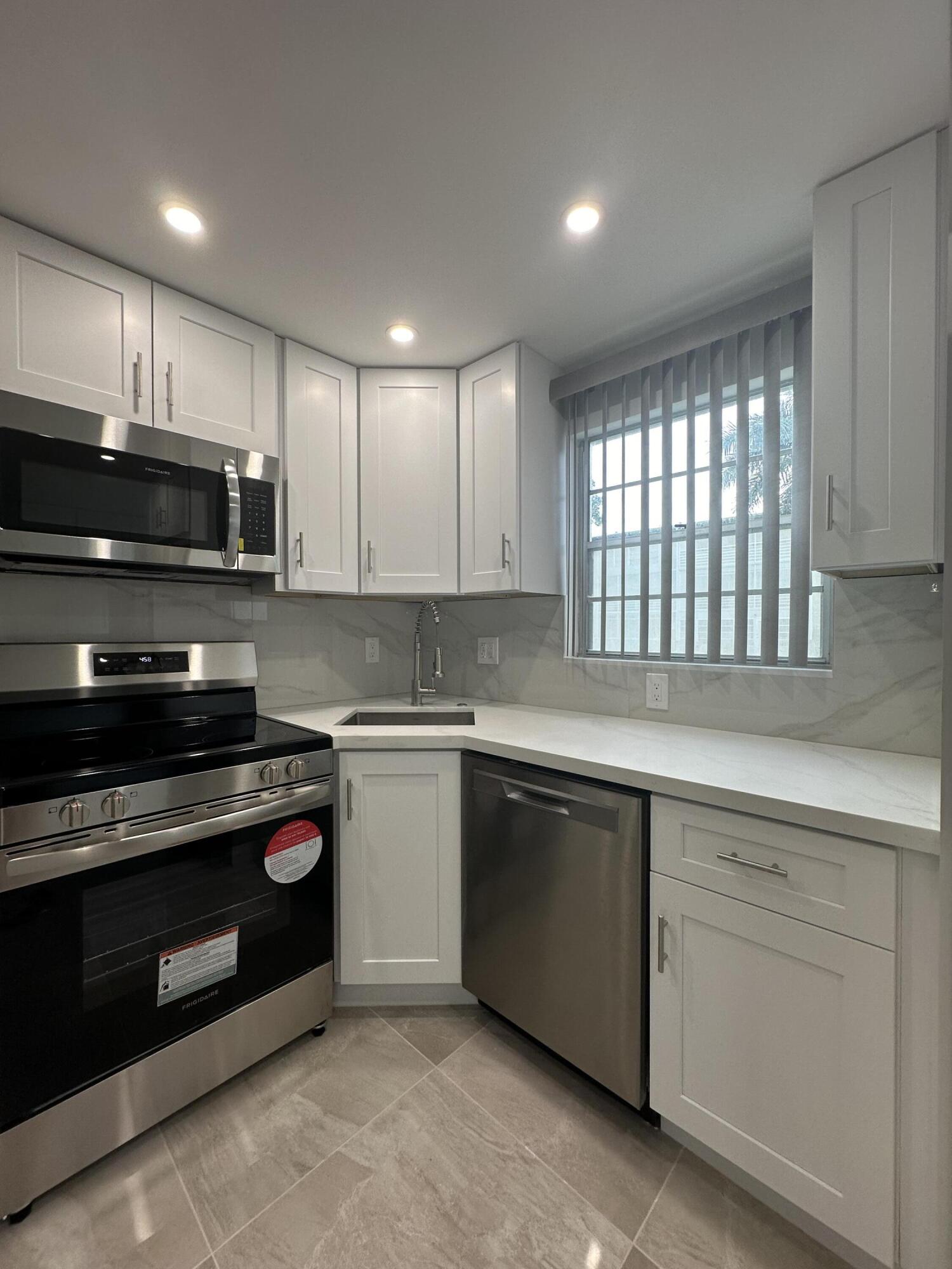 256 Suffolk F Boca Raton, FL 33434 - Photo 11 of 24 a kitchen with sink a microwave and cabinets