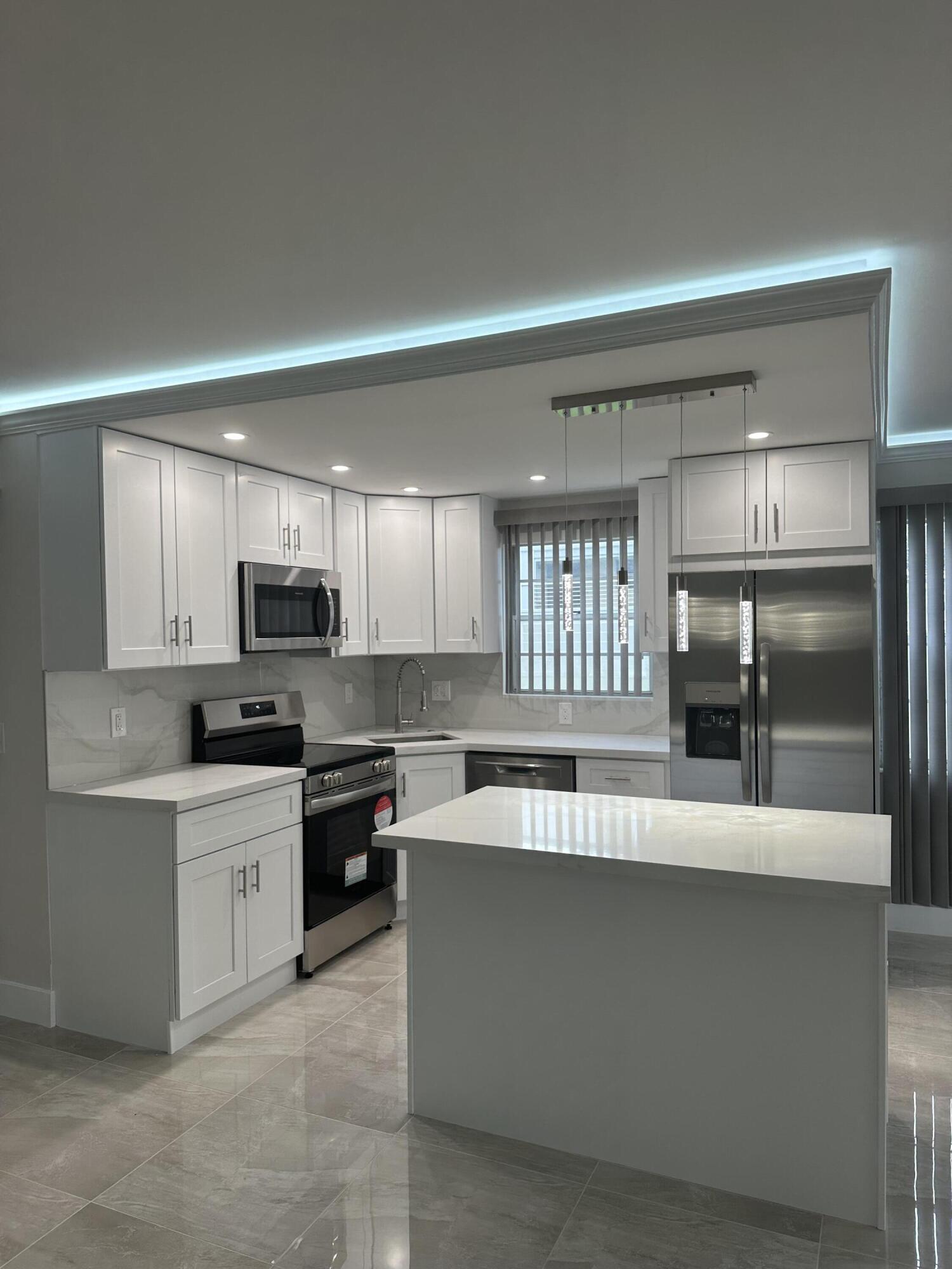 256 Suffolk F Boca Raton, FL 33434 - Photo 2 of 24 a large kitchen with a large counter top stainless steel appliances and cabinets