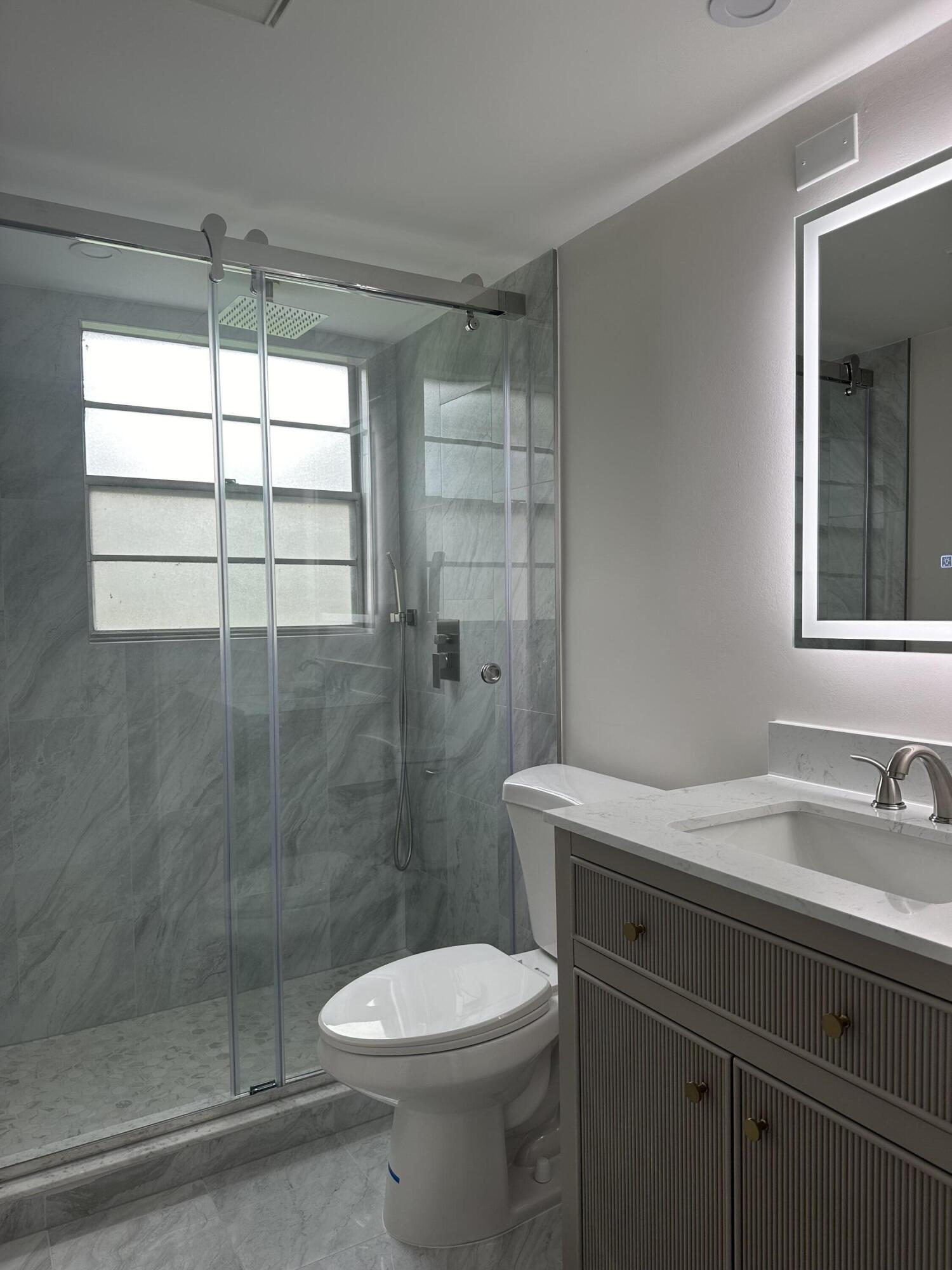 256 Suffolk F Boca Raton, FL 33434 - Photo 5 of 24 a bathroom with a sink a toilet and shower