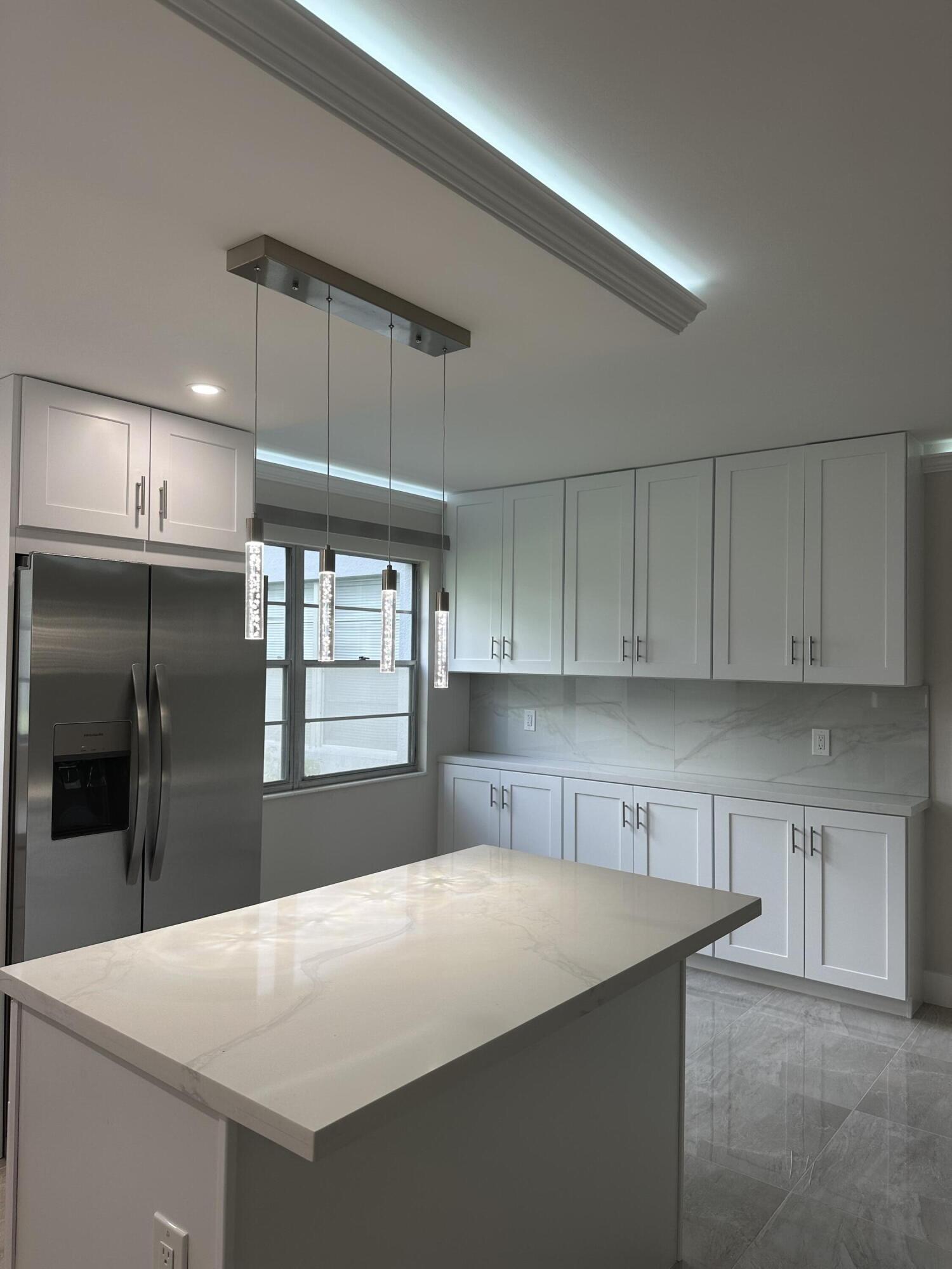 256 Suffolk F Boca Raton, FL 33434 - Photo 9 of 24 a kitchen with kitchen island a counter top a sink and a refrigerator
