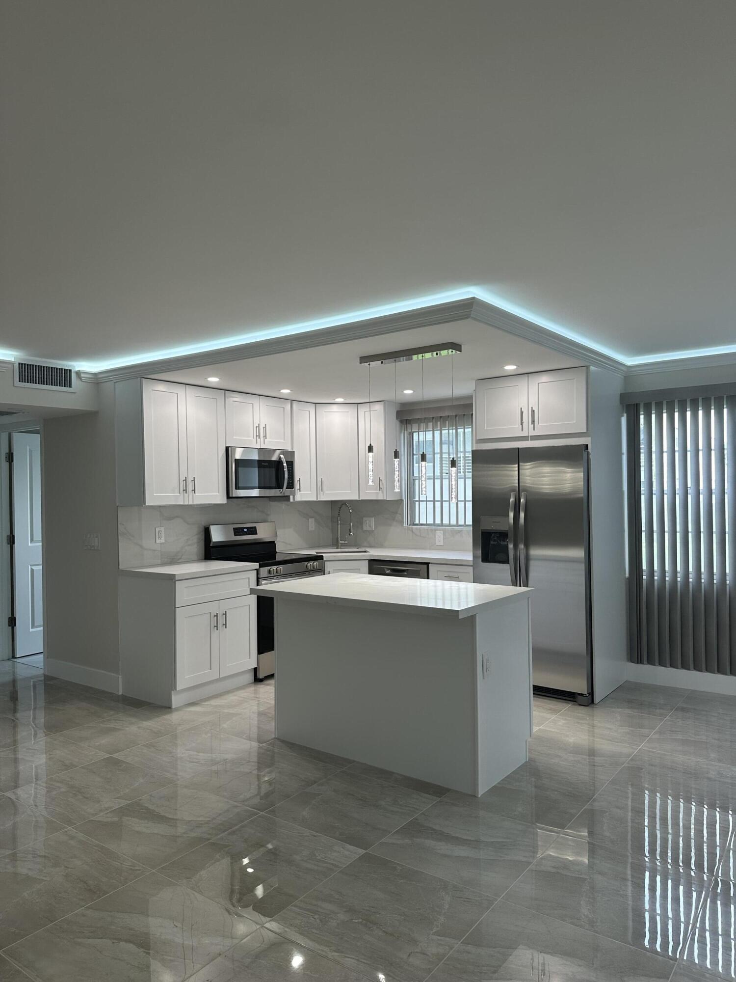 256 Suffolk F Boca Raton, FL 33434 - Photo 10 of 24 a large kitchen with kitchen island a sink stainless steel appliances and cabinets