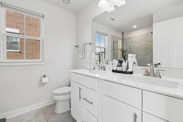 a bathroom with double vanity a toilet a and a window