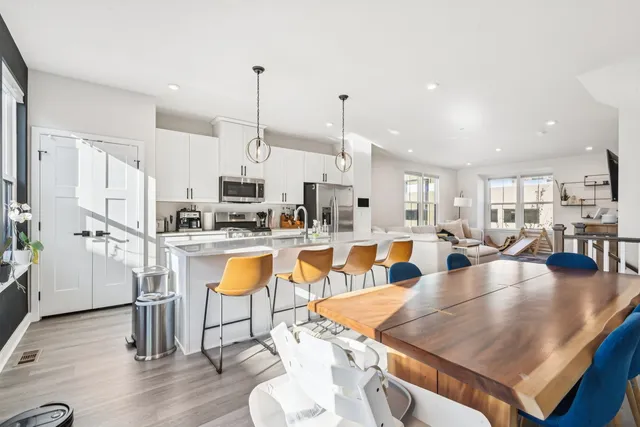 a large kitchen with stainless steel appliances granite countertop a stove a sink a dining table and chairs with wooden floor