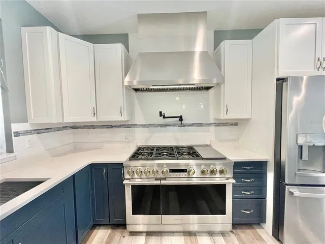 a kitchen with stainless steel appliances a stove a refrigerator and cabinets