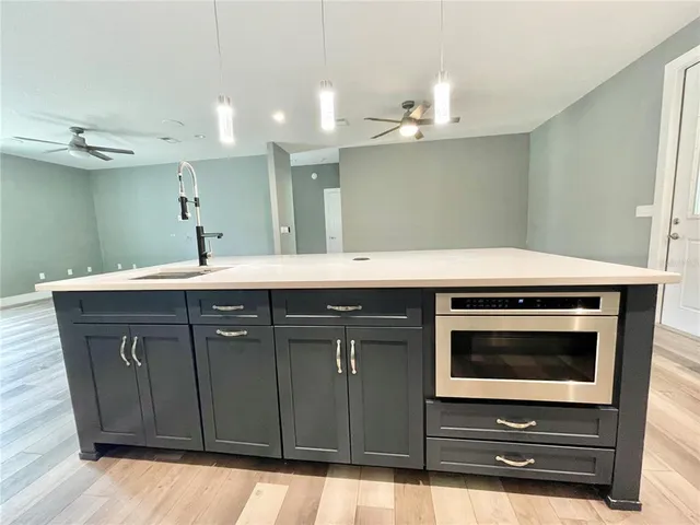 a large kitchen with stainless steel appliances kitchen island granite countertop a refrigerator and a sink