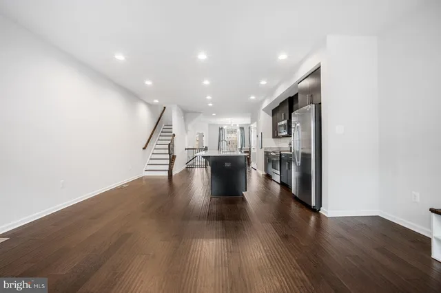 a view of a living room with kitchen view and wooden floor