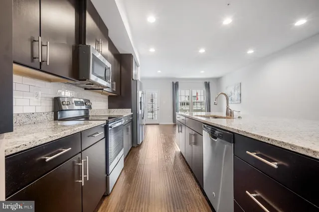 a large kitchen with stainless steel appliances granite countertop a sink and dishwasher a stove top oven with wooden floor