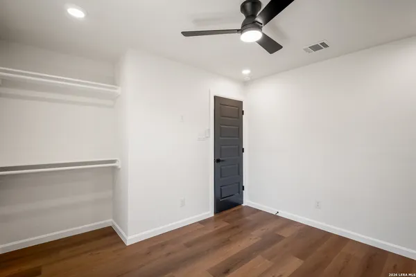 an empty room with wooden floor ceiling fan and windows