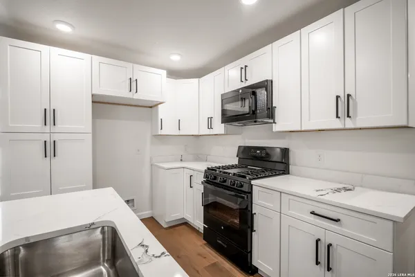 a kitchen with granite countertop white cabinets and white appliances