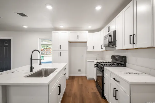 a kitchen that has a sink a stove and cabinets