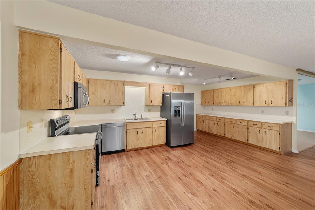 8890 Southwest 96th Street, Unit B Ocala, FL 34481 - Photo 17 of 42 a large kitchen with a wooden floor and white cabinets