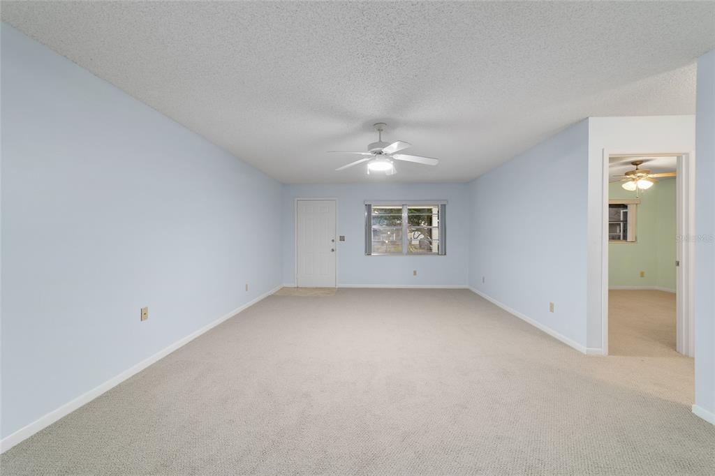 8890 Southwest 96th Street, Unit B Ocala, FL 34481 - Photo 8 of 42 an empty room with a chandelier fan and windows