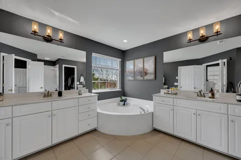 a bathroom with a double vanity sink a mirror and a bathtub