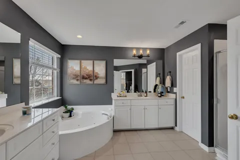 a large white bathroom with a double vanity sink a mirror and a bathtub