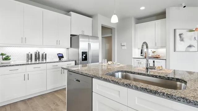 a kitchen with granite countertop a sink cabinets and wooden floor