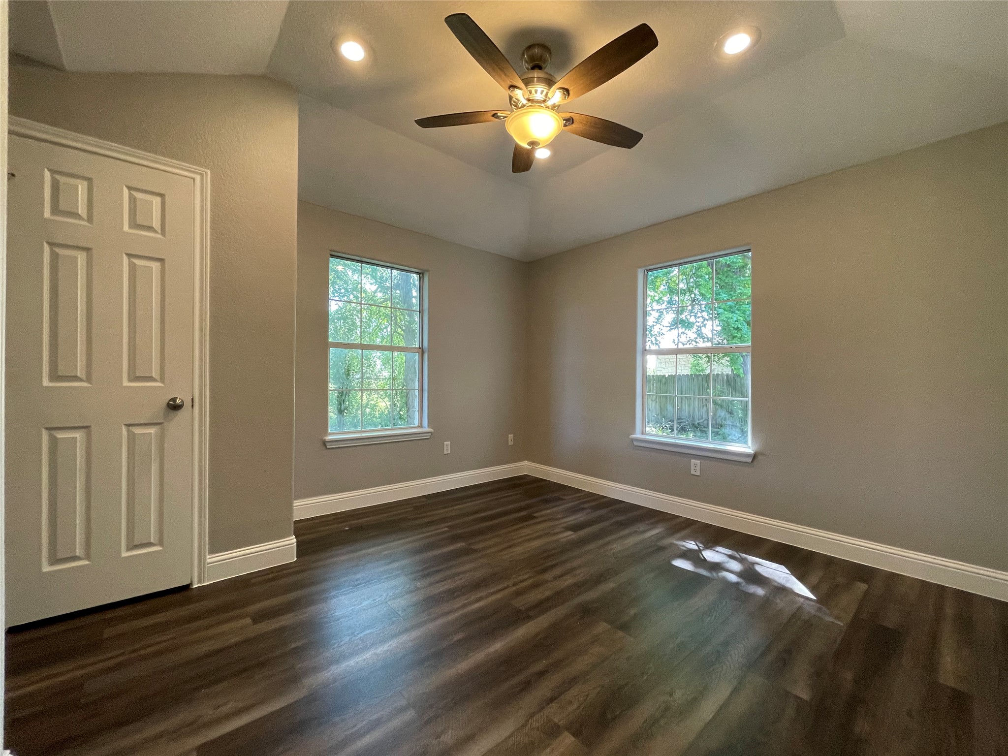 2004 Maple Street Georgetown, TX 78626 - Photo 21 of 31 Spacious room featuring wood-finish flooring, two large windows, a tray ceiling, recessed lighting, and a ceiling fan with integrated lighting