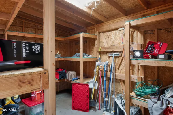 an empty room with wooden floor and way to kitchen