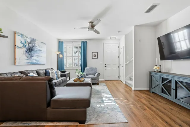 a kitchen with stainless steel appliances granite countertop a stove a sink a microwave a refrigerator and white cabinets with wooden floor