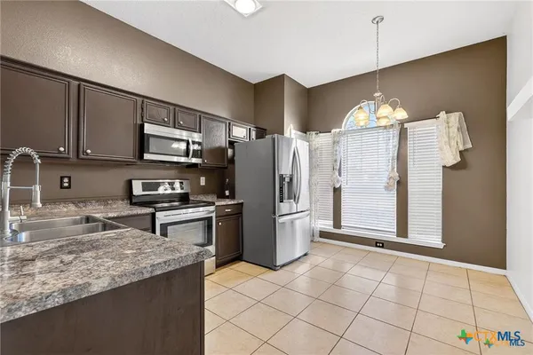 a kitchen with stainless steel appliances granite countertop a refrigerator sink and stove