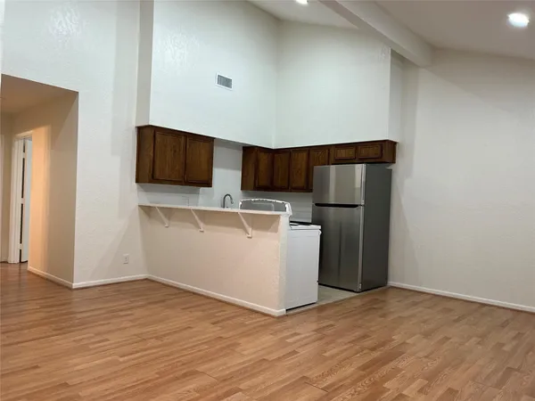 a view of kitchen with stainless steel appliances wooden floor and chair