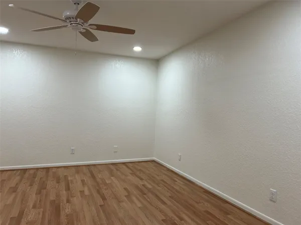 an empty room with a ceiling fan and wooden floor