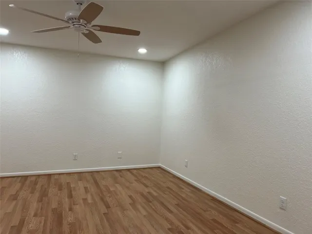 an empty room with a ceiling fan and wooden floor
