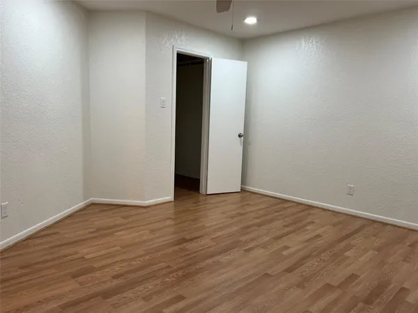 a view of an empty room with wooden floor and closet