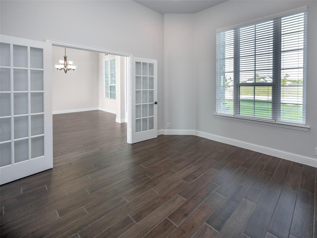2108 Charters Circle Nevada, TX 75173 - Photo 16 of 37 Empty room with dark wood finished floors and a chandelier