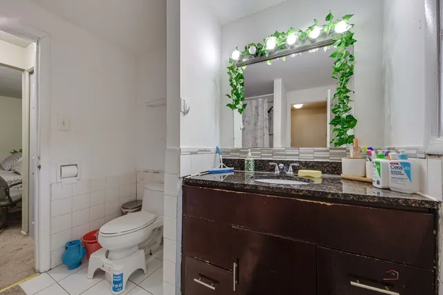 a bathroom with a granite countertop sink a toilet and a mirror