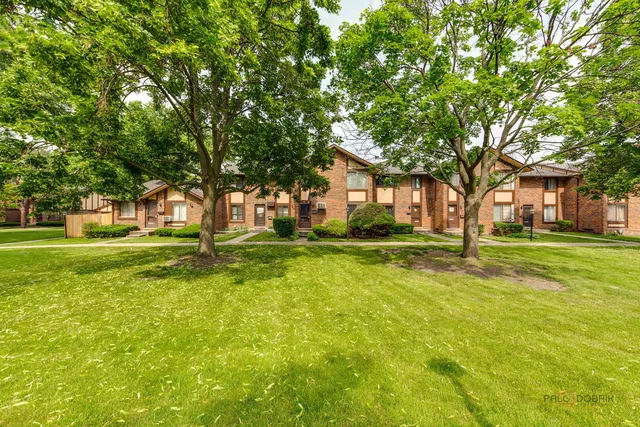 a view of a house with a big yard and large trees