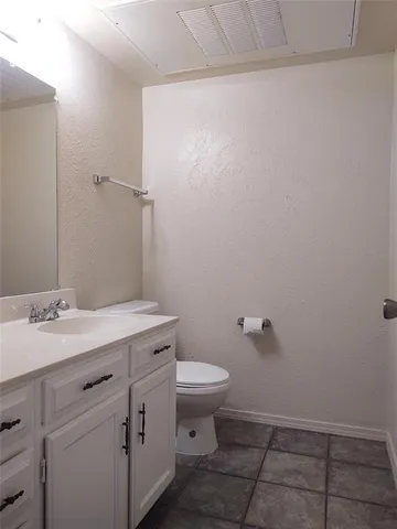 a bathroom with a granite countertop sink a toilet and a mirror