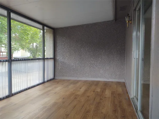 en empty room with wooden floor and windows