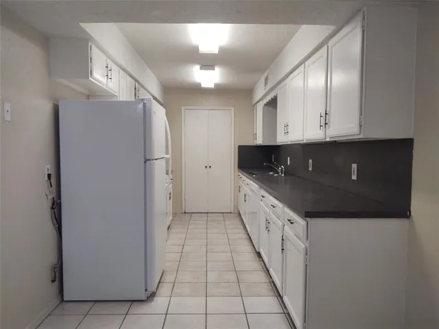 a large white kitchen with a sink and refrigerator