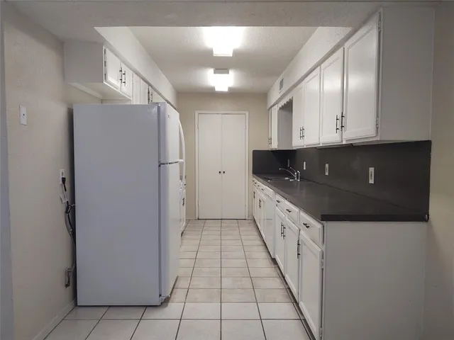 a kitchen with granite countertop a refrigerator a sink and dishwasher