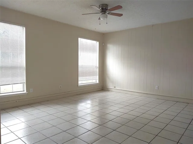 an empty room with windows and fan
