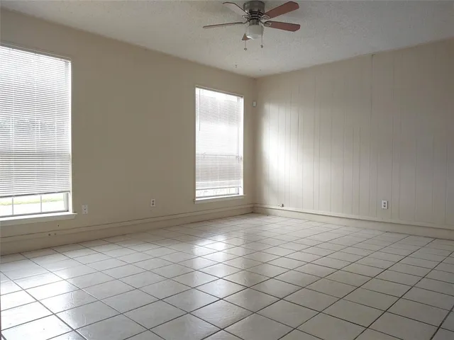 an empty room with windows and fan